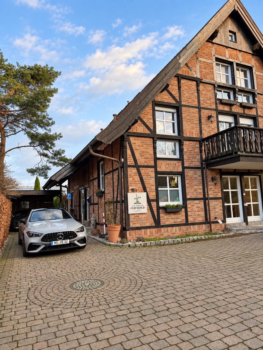 Das Landhotel bei Tageslicht mit einem Mercedes links auf dem Hof